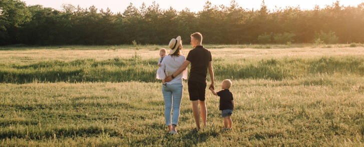Junge Familie im Familienurlaub auf einer Wiese mit zwei Kleinkindern
