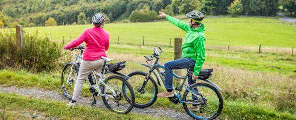 Zwei Frauen zeigen in die Natur während einer Fahrradtour.