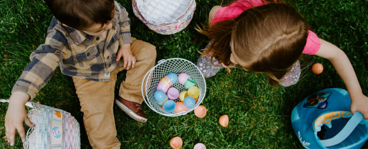 Zwei Kinder mit einem Osterkorb und bunten Eiern