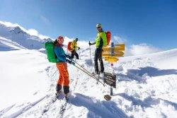 Skiwanderer vor einem Schild bei strahlendem Sonnenschein
