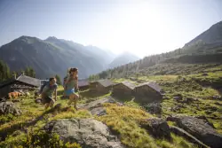 Wanderer auf Wanderweg im Montafon mit Berghütten und Berggipfeln im Hintergrund