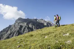 Zwei Wanderer auf einer Wanderung im Montafon mit einem Bergmassiv im Hintergrund