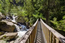 Brücke über kleinen Fluss mit Wasserfall auf Wanderweg im Montafon