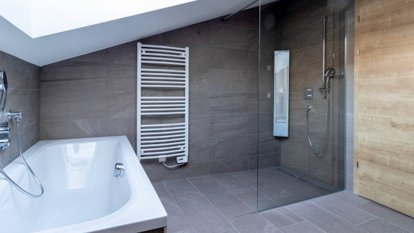 Modernes Badezimmer in Betonoptik mit begehbarer Infrarotdusche und Badewanne in Unterkunft direkt an der Skipiste in Sankt Gallenkirch, Vorarlberg